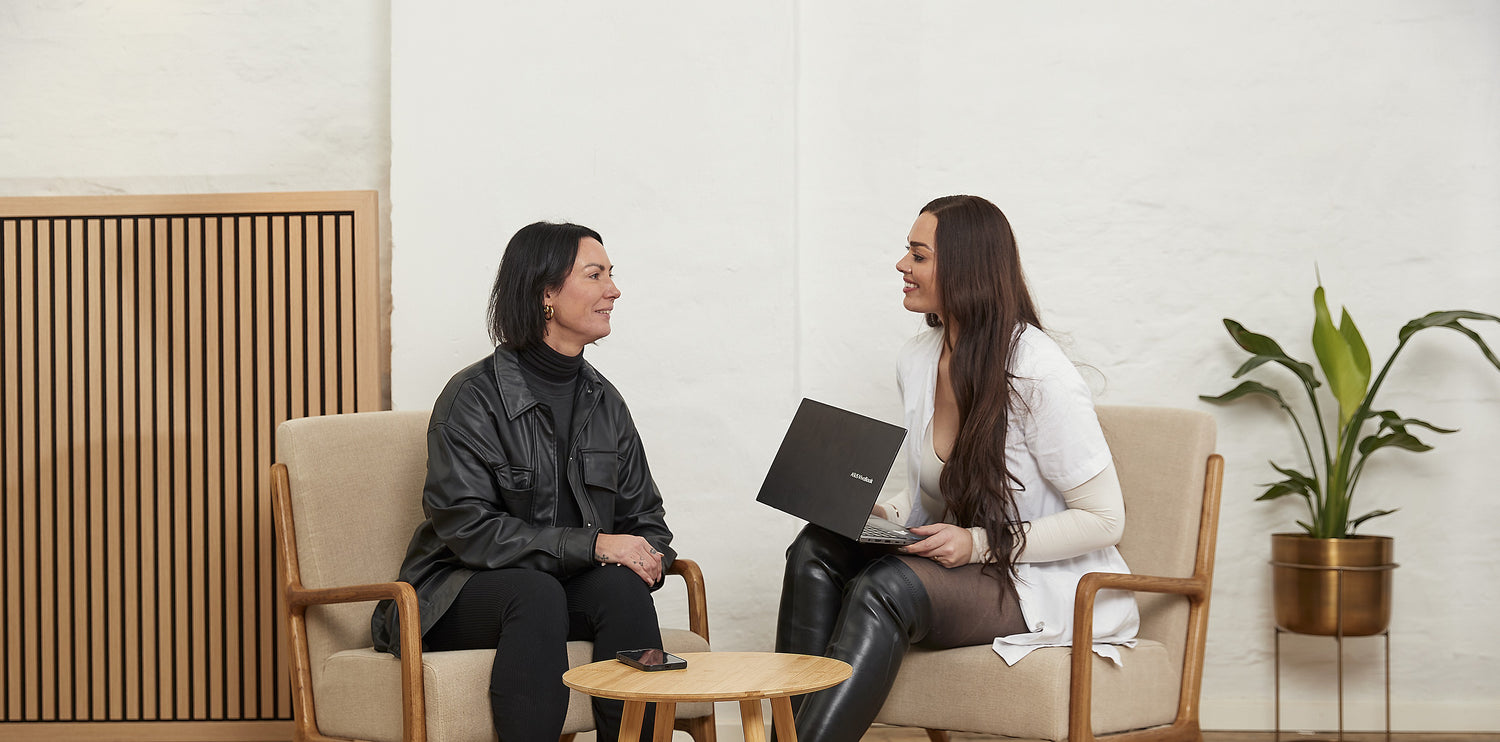 Kosmetisk konsultation hos Cosmo Laser: Kunde og behandler gennemgår laserbehandling på bærbar computer.