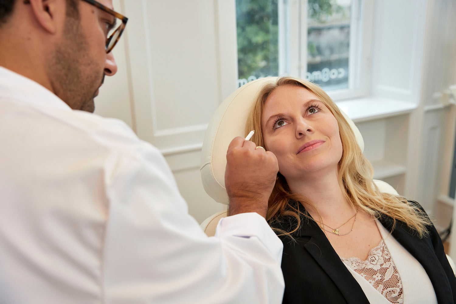 Kosmetisk læge hos Cosmo Laser markerer ansigtszoner før fillerbehandling.