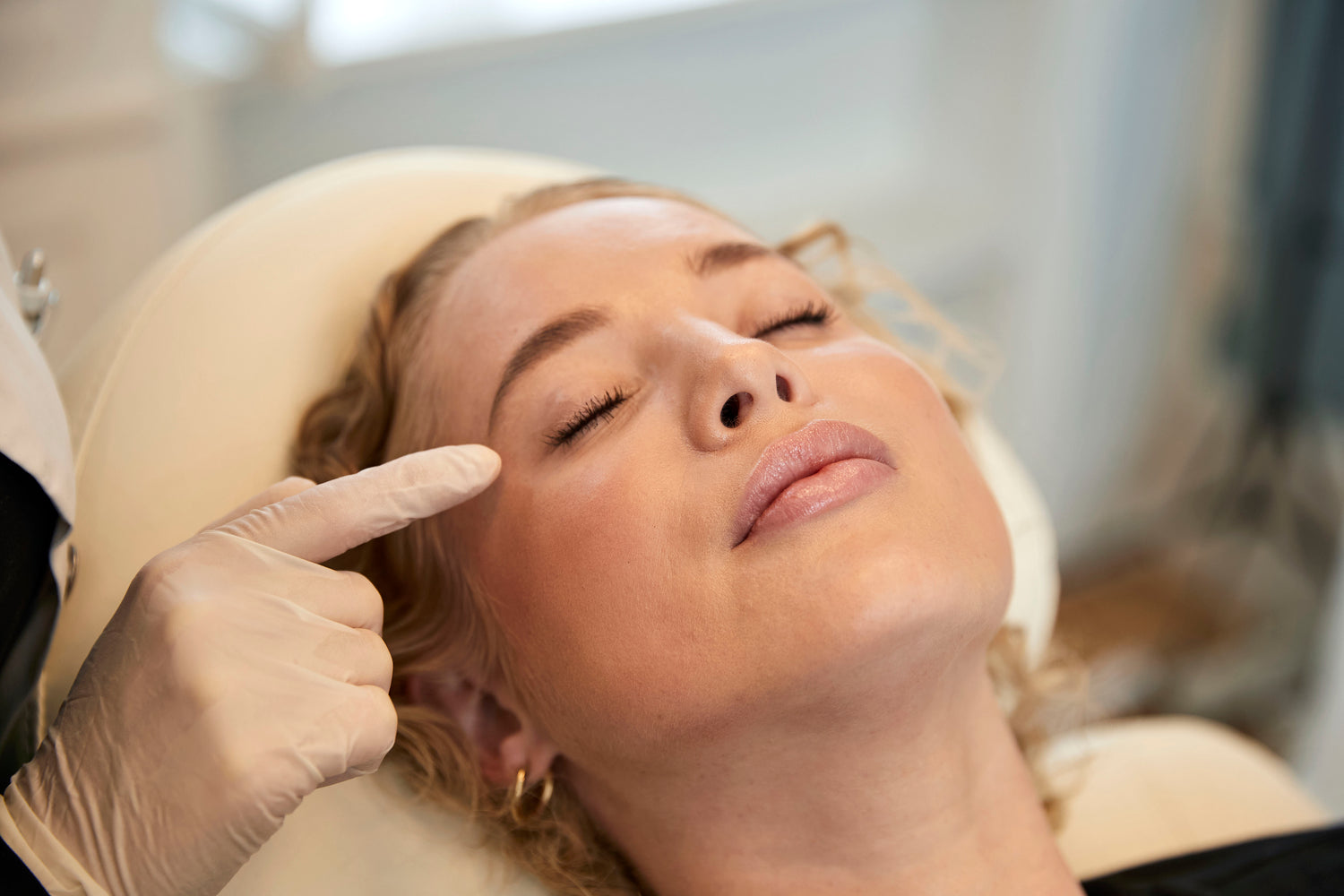Kosmetisk behandler hos Cosmo Laser undersøger kvindes ansigt før fillerbehandling.