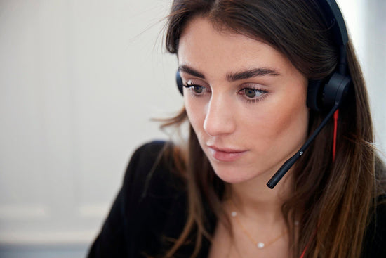 Kundeservicemedarbejder hos Cosmo Laser København med headset, klar til at besvare spørgsmål om laserbehandling.