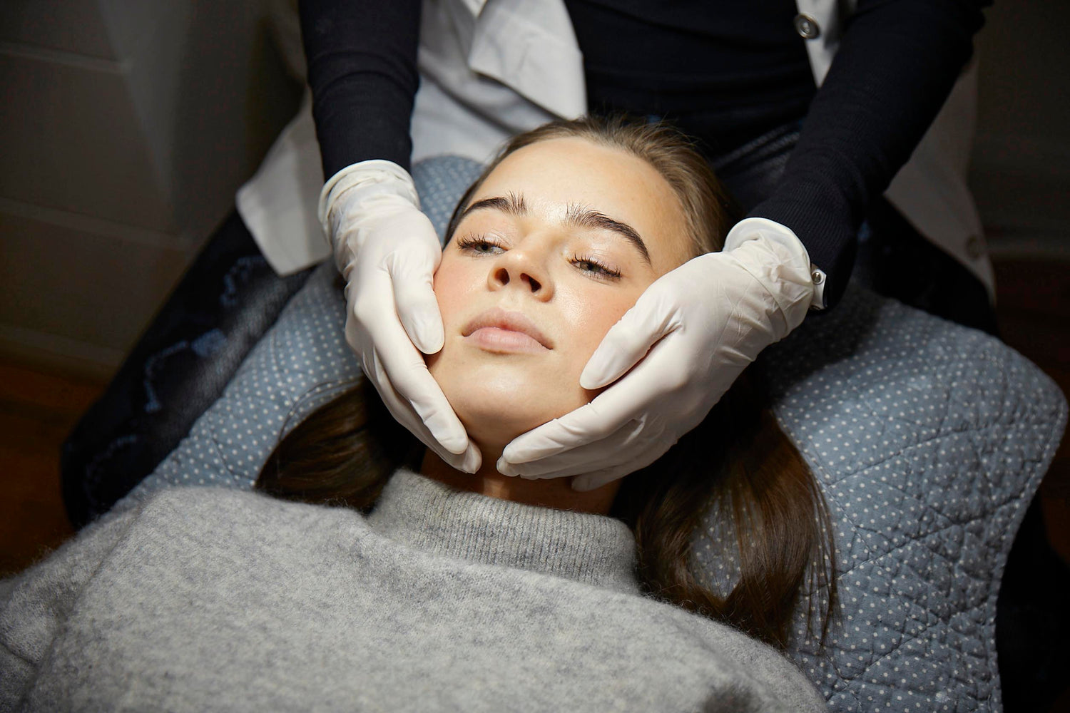 Kosmetisk behandling hos Cosmo Laser: Nærbillede af ansigt under skånsom ansigtsbehandling med handsker.