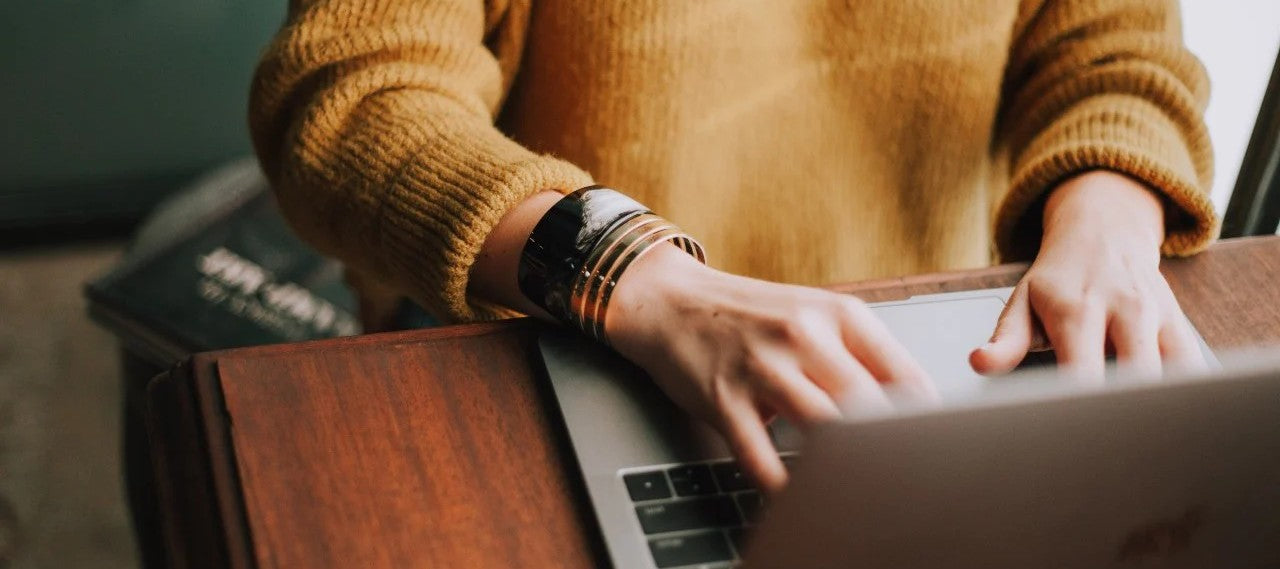 Hænder på tastatur, der booker laserbehandling hos Cosmo Laser København.