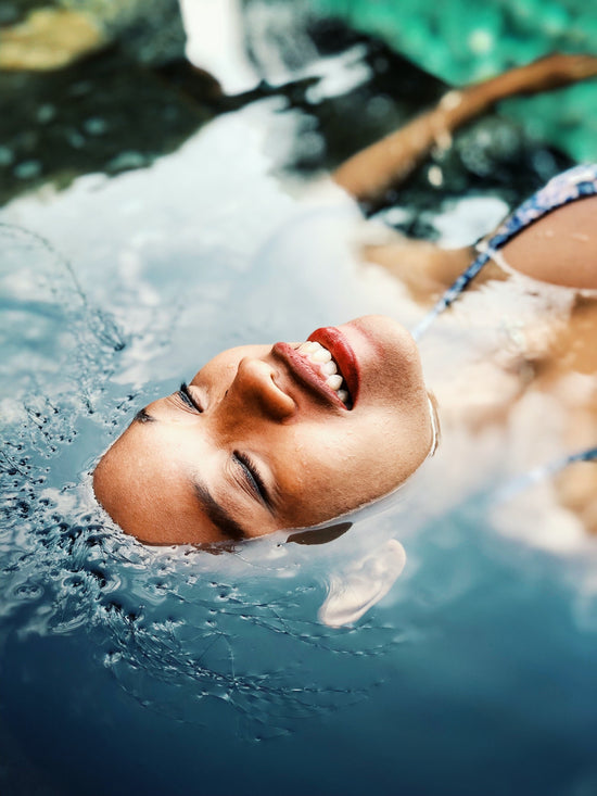 Kvinde ligger og flyder i vandet med ansigtet oppe