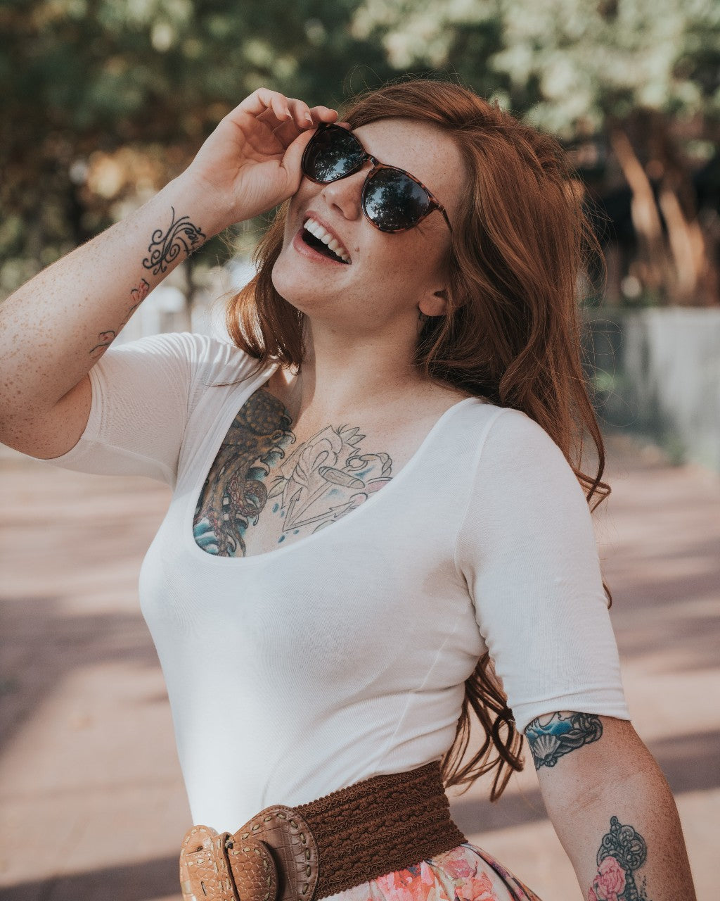 Kvinde med tatoveringer står med solbriller udenfor